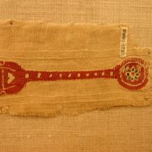 A tapestry woven band with a rose background the band narrows then widens back out to a circle.