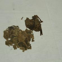 Very small samite fragments depicting part of a huntsman and a lion